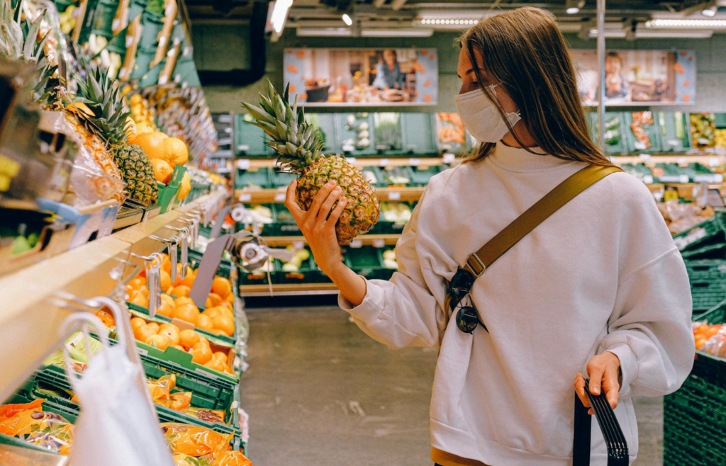 Woman holding pineapple, deciding on fruit choice