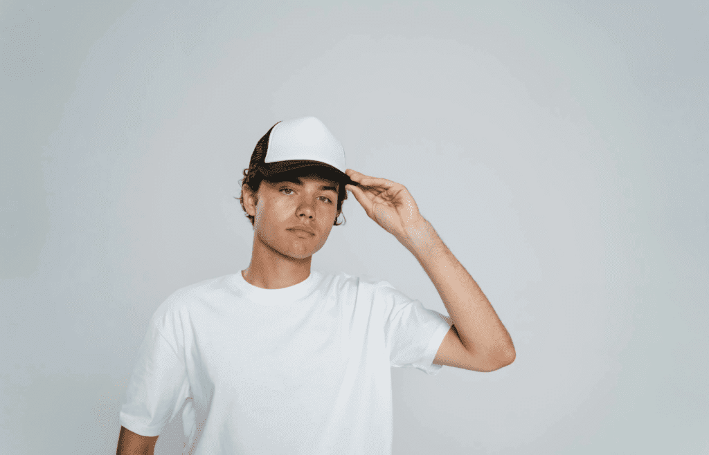A person wearing a flat-brimmed trucker hat with a logo