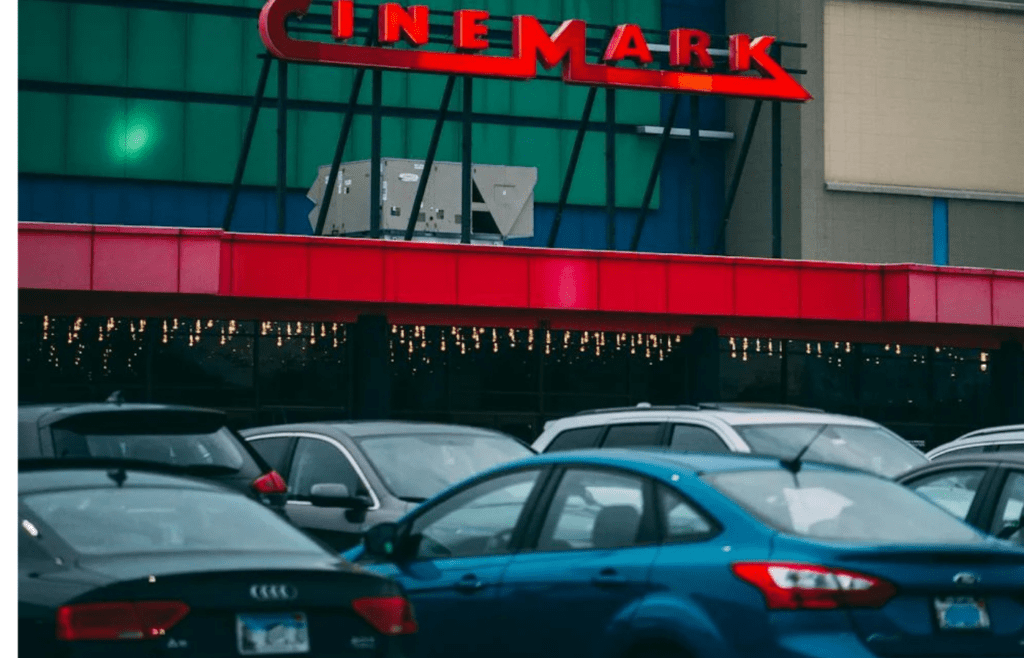 Cars parked in front of a large outdoor movie screen