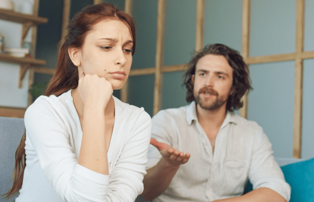 Two people mid-disagreement, one raising a calming hand