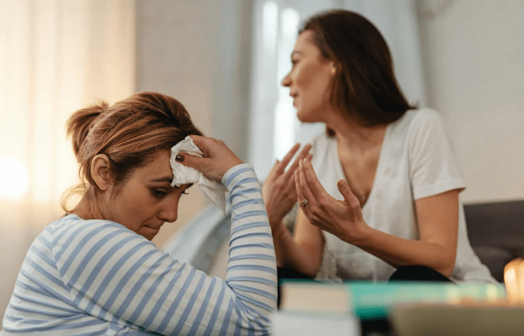 A person yelling during an argument while the other looks distraught