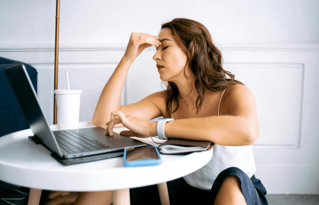 A stressed person surrounded by paperwork and coffee cups