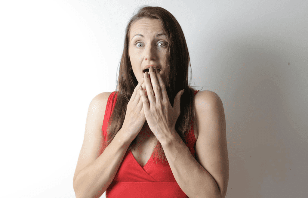 A surprised older woman with hands on cheeks