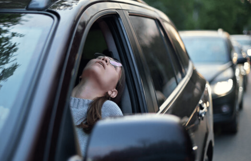 A frustrated person stuck in traffic or a boring event
