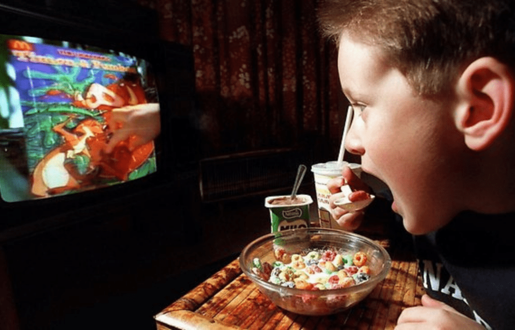 A kid eating cereal in front of a TV