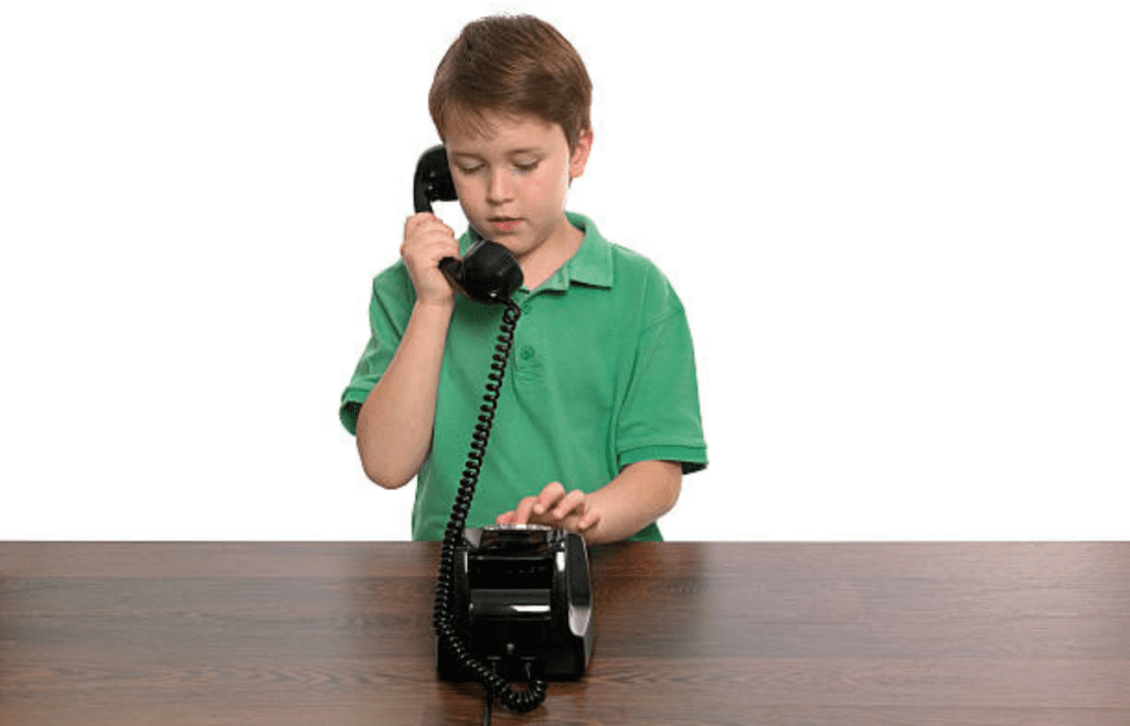 A kid using a landline phone with a notepad nearby