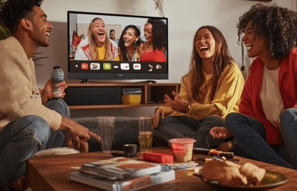 A family watching TV together, snacks on the coffee table