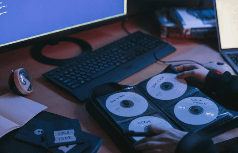 A desktop computer with a CD tray open and a stack of blank CDs