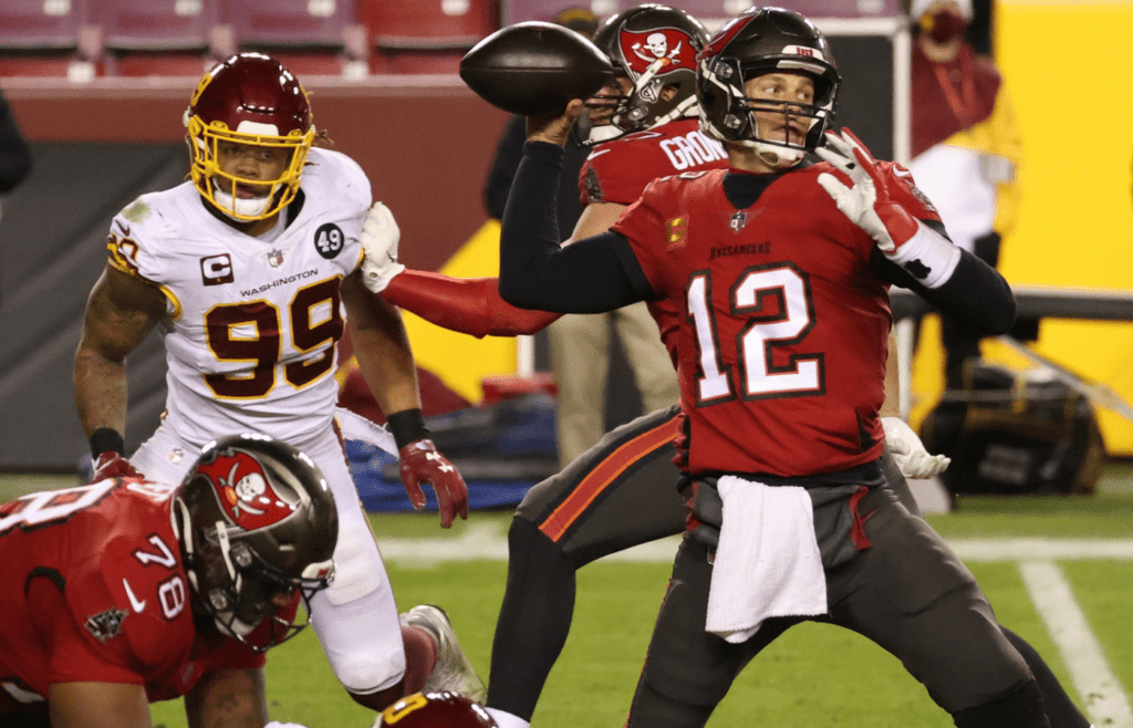 Jan 9, 2021; Landover, Maryland, USA; Tampa Bay Buccaneers quarterback Tom Brady (12) passes the ball as Washington Football Team defensive end Chase Young (99) chases in the fourth quarter at FedExField. Mandatory Credit: Geoff Burke-Imagn Images