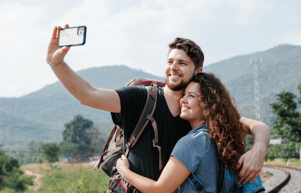 Happy couple capturing moment on smartphone outside