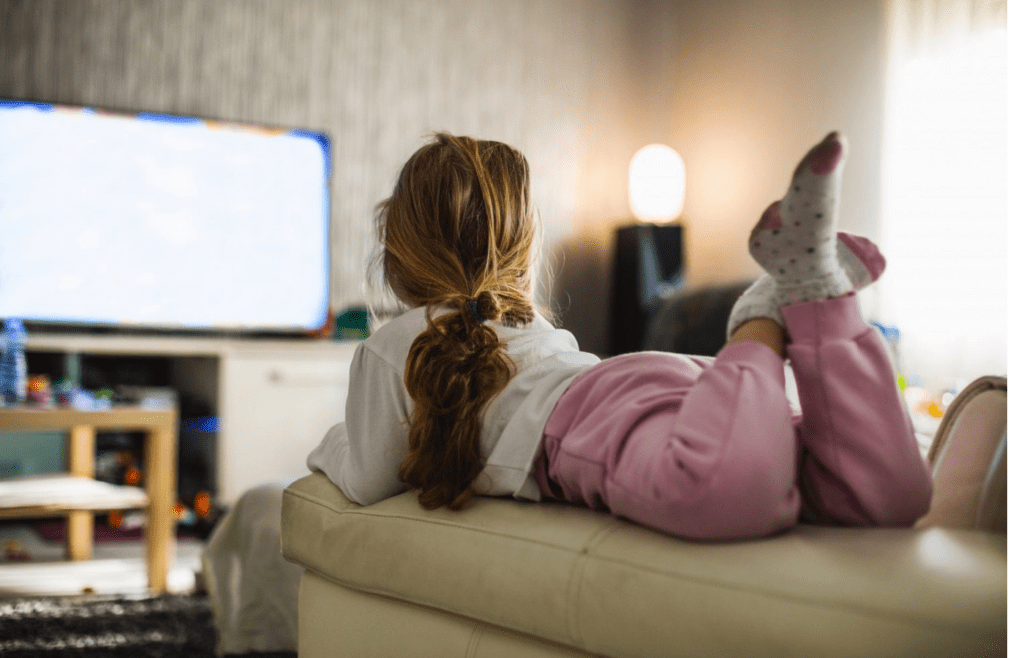A child watching TV alone on a couch