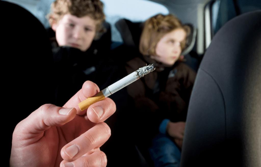 A driver with a cigarette and kids in the backseat