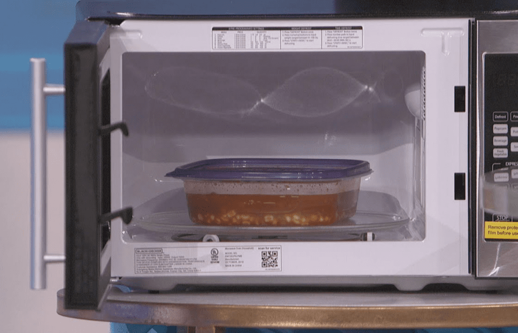 An old microwave with a steaming plastic container inside