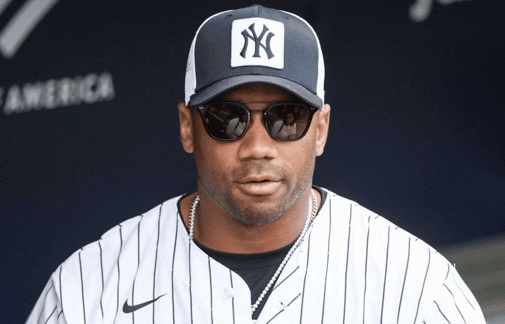May 18, 2025; Bronx, New York, USA; New York Giants quarterback Russell Wilson watches batting practice prior to the game between the New York Mets and the New York Yankees at Yankee Stadium. Mandatory Credit: Wendell Cruz-Imagn Images