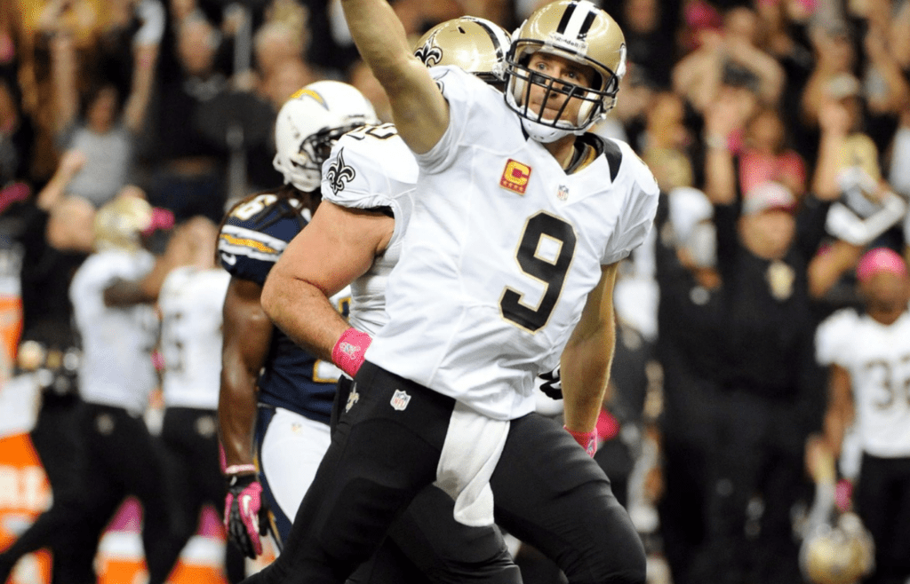 October 7, 2012; New Orleans, LA, USA; New Orleans Saints quarterback Drew Brees (9) celebrates after throwing a first quarter touchdown pass during their game against the San Diego Chargers at Mercedes-Benz Superdome. Brees broke an NFL record previously held by Johnny Unitas for most consecutive games with a touchdown pass. Mandatory Credit: Chuck Cook - Imagn Images