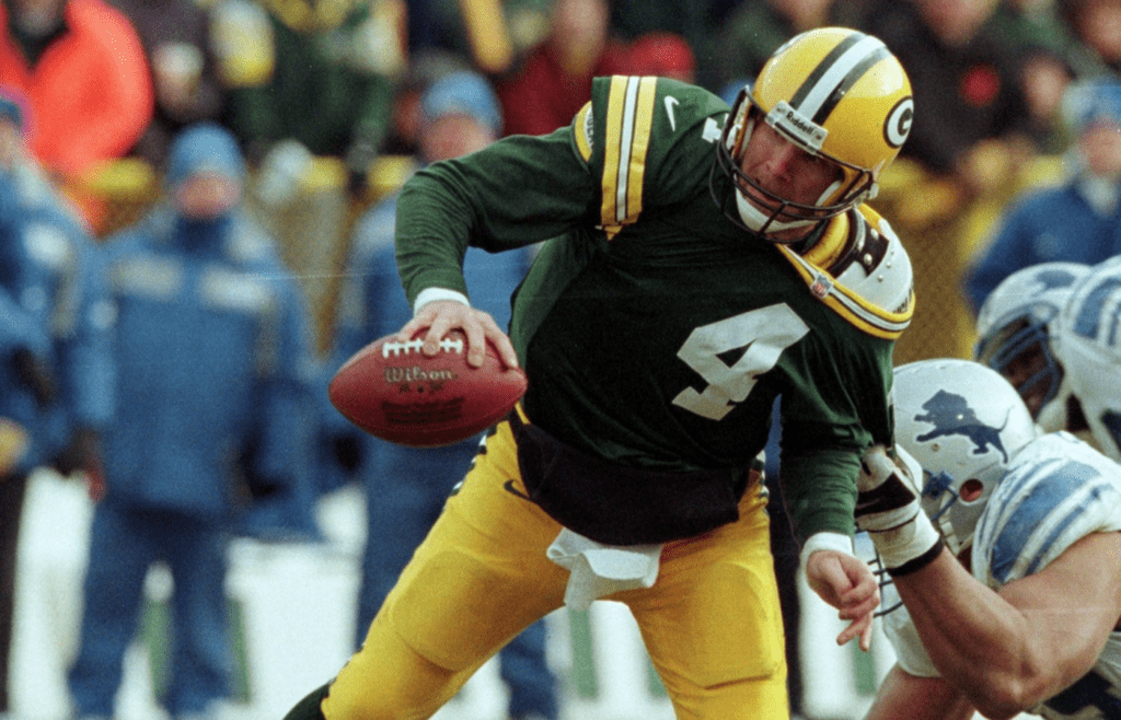 Green Bay Packers quarterback Brett Favre is able to get off a pass despite being dragged by Detroit Lions Luther Ellis during the second quarter of their game on Dec. 10, 2000 at Lambeau Field in Green Bay, Wis