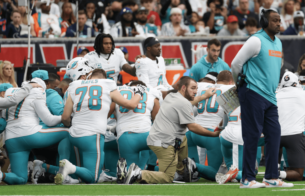 Dec 15, 2024; Houston, Texas, USA; The Miami Dolphins pray on the sidelines as the medical team works on wide receiver Grant DuBose (88) (not pictured) after he was injured when he was tackled by Houston Texans safety Calen Bullock (21) (not pictured) in the third quarter at NRG Stadium. Mandatory Credit: Thomas Shea-Imagn Images