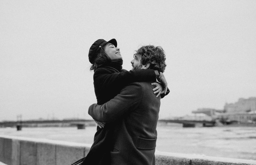 A couple hugging tightly outdoors