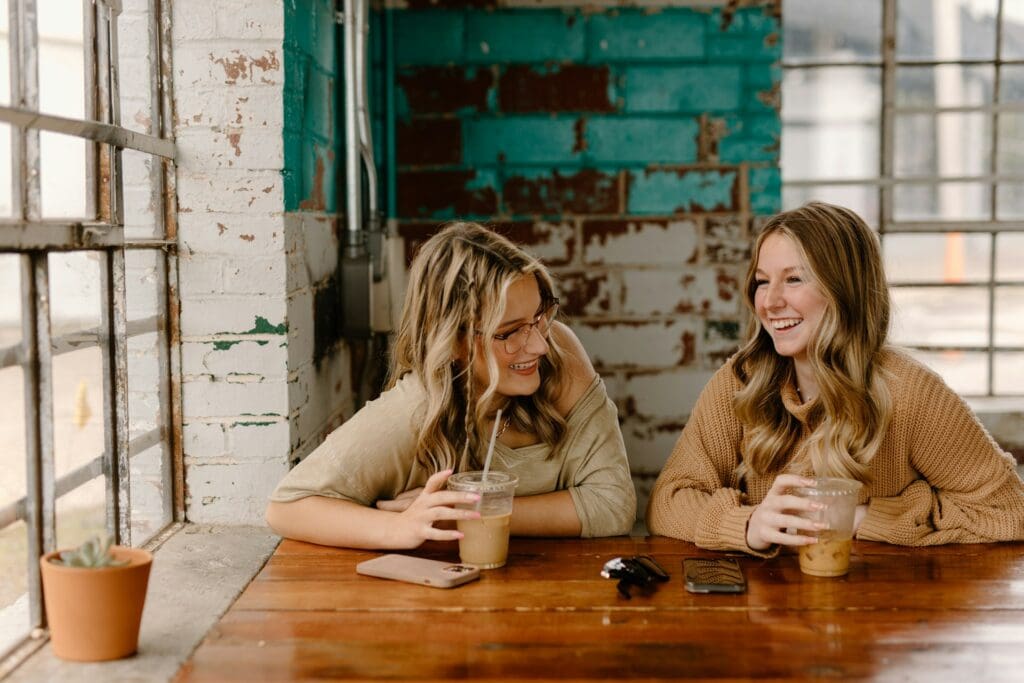 A person laughing with friends at a coffee shop
