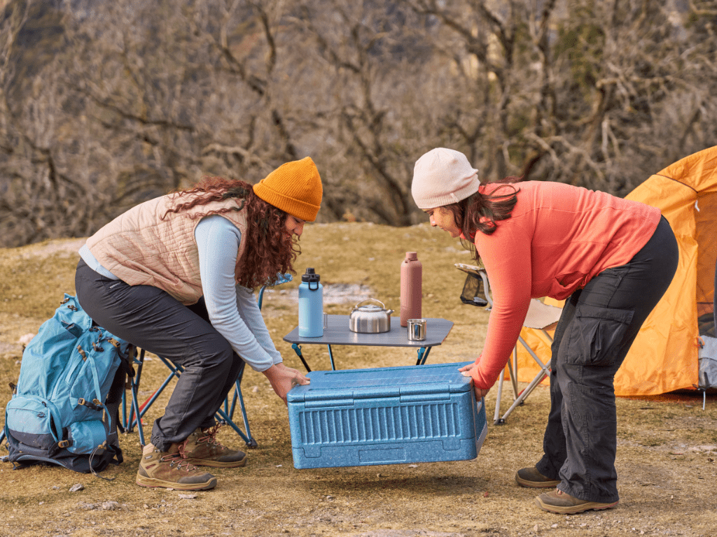 two women carrying a cooler