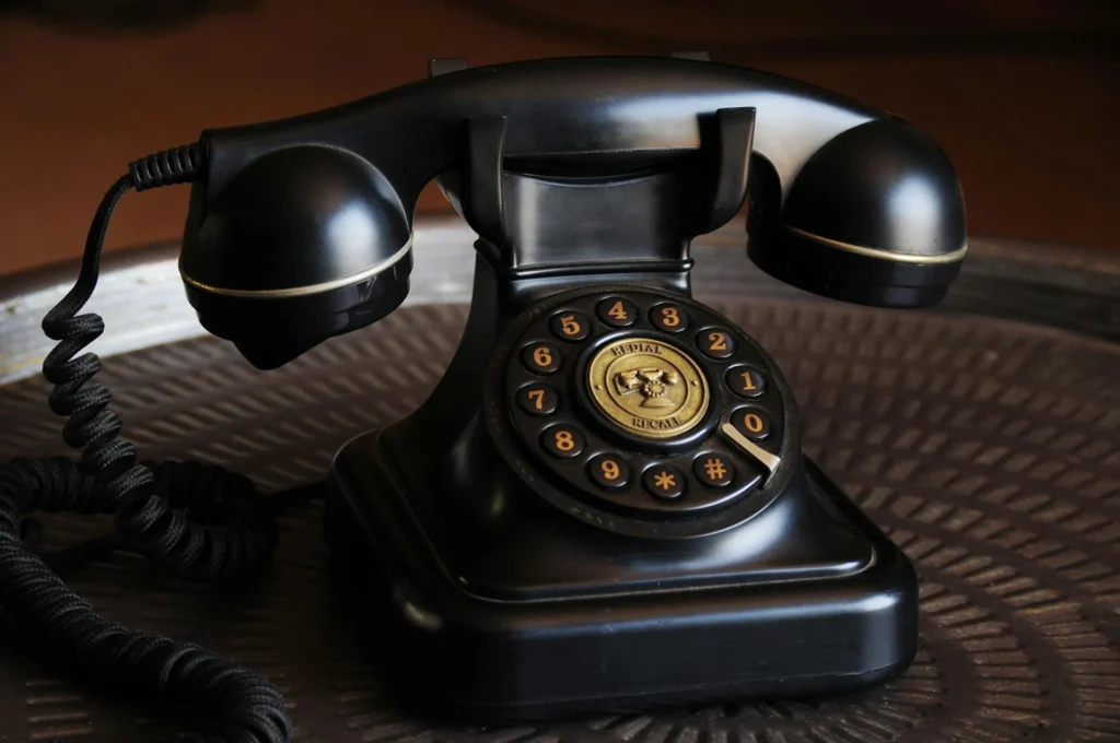 : A black rotary dial telephone on a wooden table