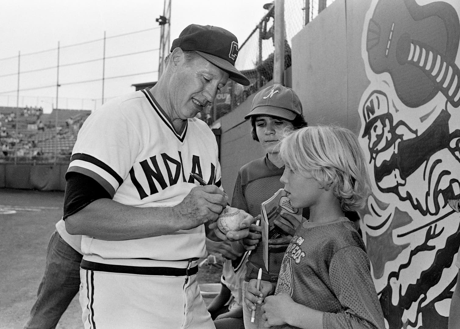 Former Cleveland Indians great Bob Feller autographs a ball for Steve Craig, right, as Gary Winfrey waits his turn with a program during the Hall of Famer pitcher special appearance for the Nashville Sounds game at Greer Stadium Aug. 2, 1979. 79then08 001