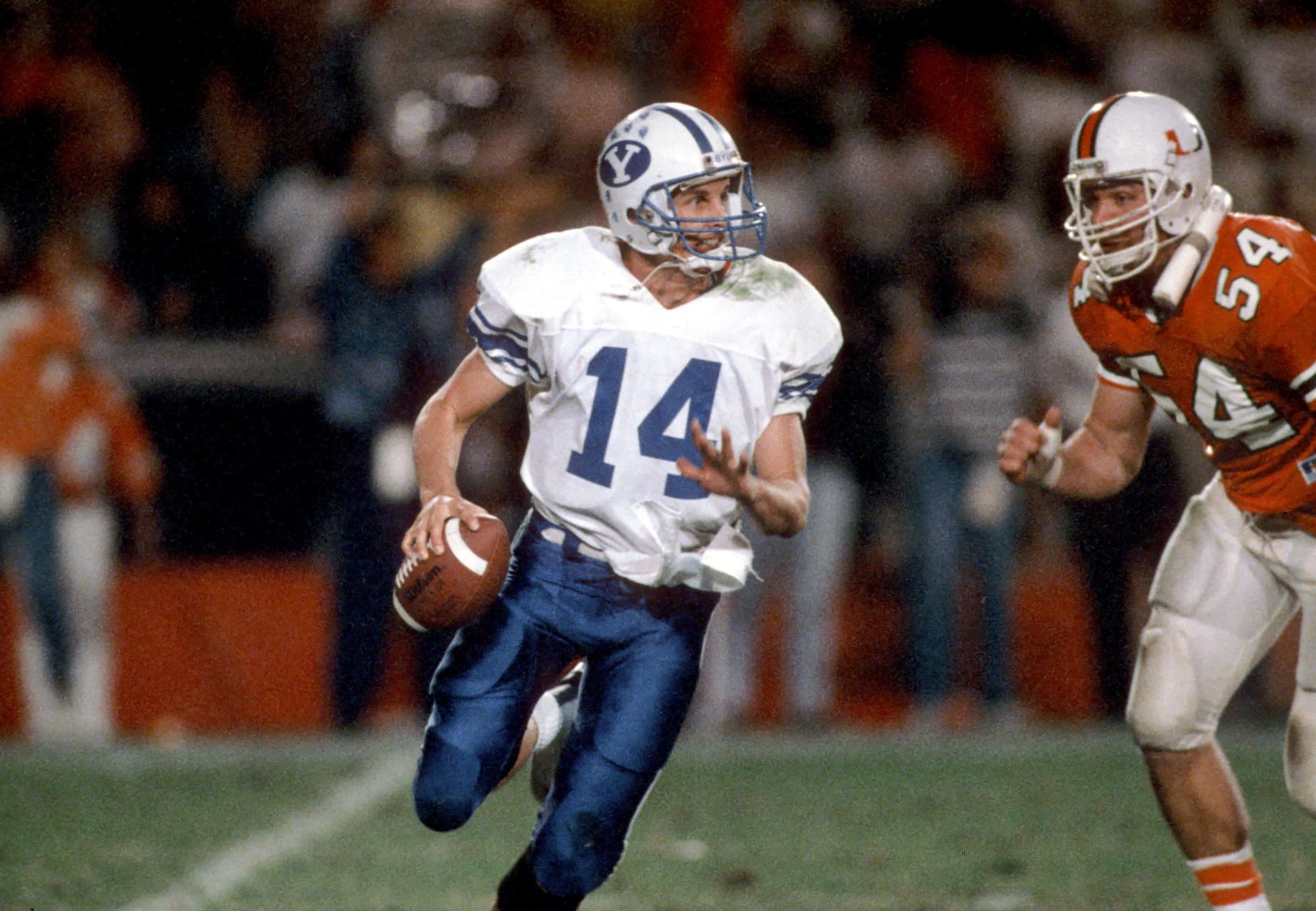 Dec 3, 1988; Miami, FL, USA; FILE PHOTO; Brigham Young quarterback #14 TY DETMER is chased by Miami Hurricanes defensive end #54 BILL HAWKINS during the 1988 season at the Orange Bowl. Miami defeated BYU 41-17. Mandatory Credit: Photo By USA TODAY Sports © Copyright USA TODAY Sports