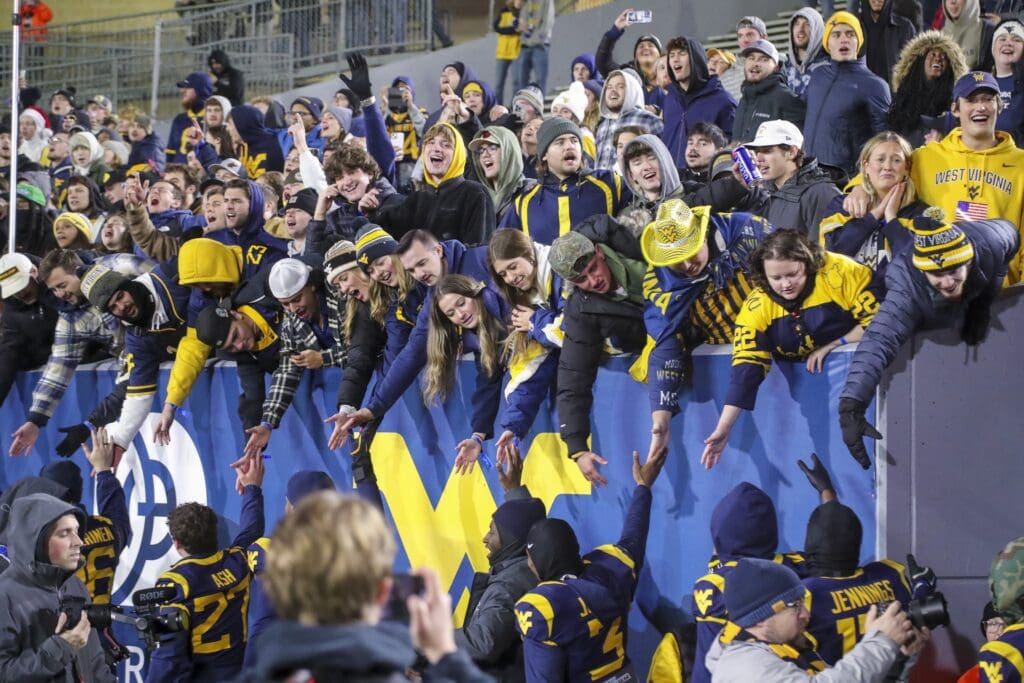 Nov 23, 2024; Morgantown, West Virginia, USA; West Virginia Mountaineers fans celebrate with players after defeating the UCF Knights at Mountaineer Field at Milan Puskar Stadium. Mandatory Credit: Ben Queen-Imagn Images