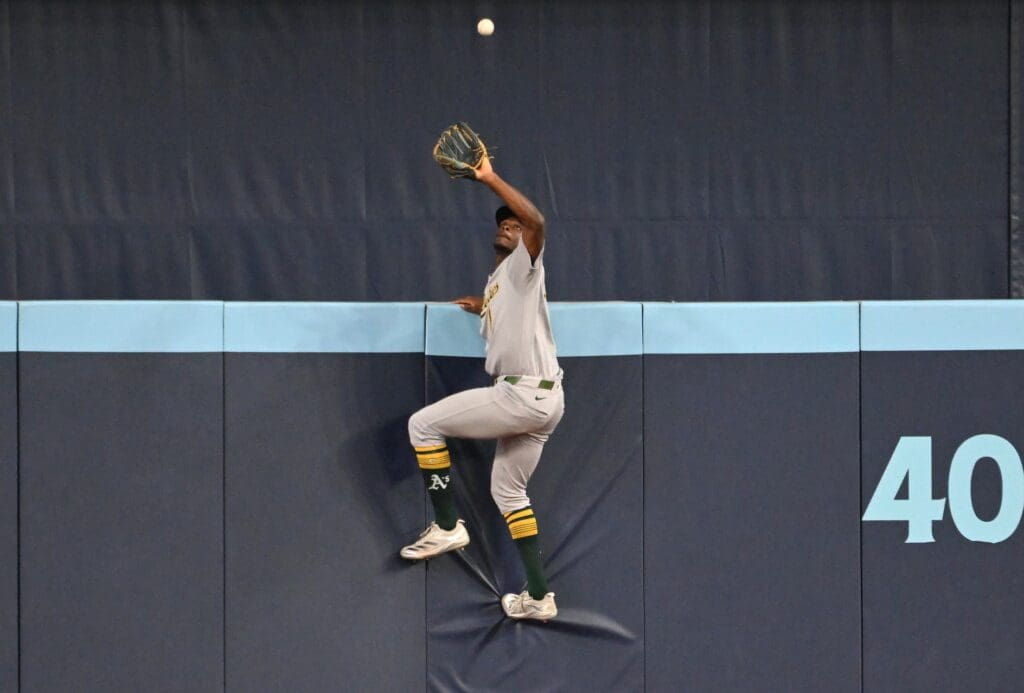 May 30, 2025; Toronto, Ontario, CAN; Athletics center fielder Denzel Clarke (1) climbs the outfield wall to catch a fly ball hit by Toronto Blue Jays catcher Alejandro Kirk (not shown) in the fifth inning at Rogers Centre. Mandatory Credit: Dan Hamilton-Imagn Images