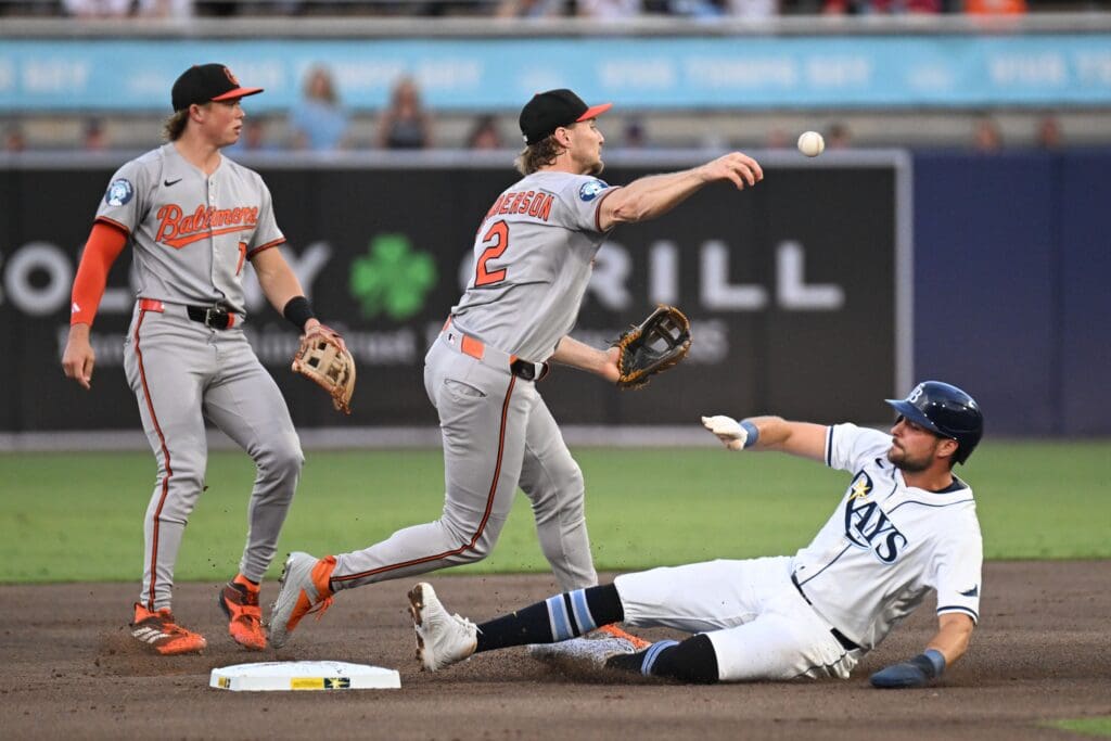 Jun 17, 2025; St. Petersburg, Florida, USA; Baltimore Orioles shortstop Gunner Henderson (2) throws to first base as Tampa Bay Rays right fielder Josh Lowe (15) slides in the first inning at George M. Steinbrenner Field. Mandatory Credit: Jonathan Dyer-Imagn Images