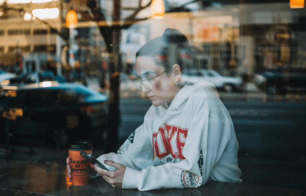 A person holding their phone out in front of them in a coffee shop