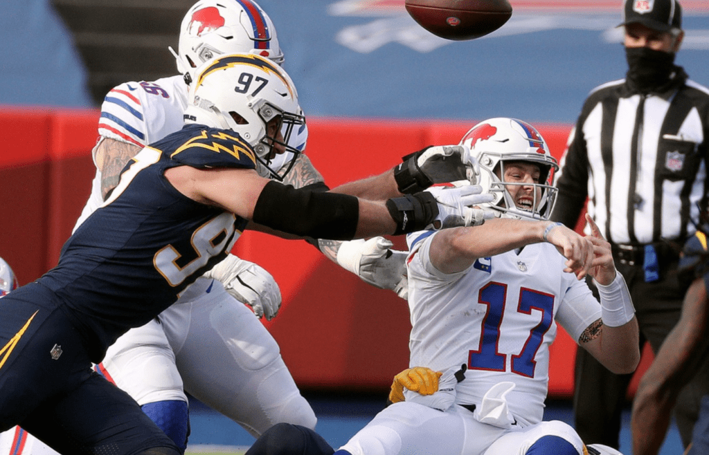 Bills quarterback Josh Allen throws way a pass as he is being hauled down by Chargers Isaac Rochell and Joey Bosa. The Bills beat the Chargers 27-17 but Allen was sack3d twice and hurried much of the game. Jg 112920 Bills 3
