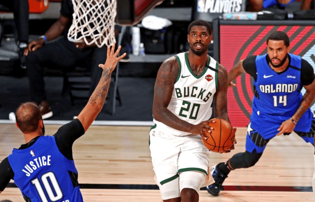Aug 29, 2020; Lake Buena Vista, Florida, USA; Milwaukee Bucks forward Marvin Williams (20) drives to the basket against Orlando Magic guard Evan Fournier (10) and guard D.J. Augustin (14) during the second quarter in game five of the first round of the 2020 NBA Playoffs at AdventHealth Arena. Mandatory Credit: Kim Klement-Imagn Images