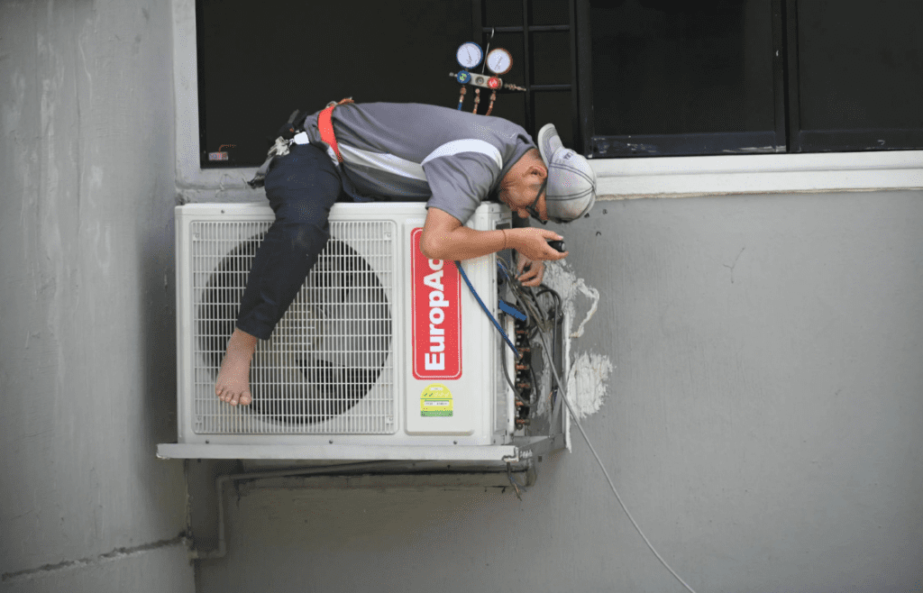 A technician servicing an air conditioning unit