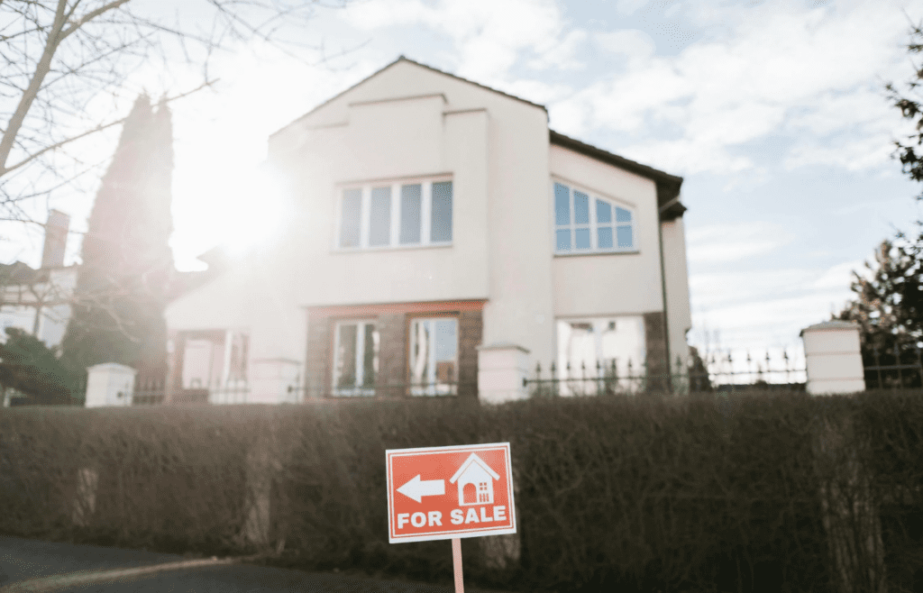 A for-sale sign in front of a large house