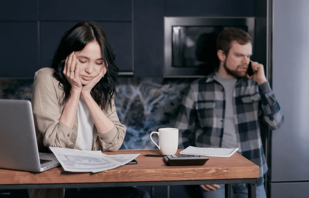 A person overwhelmed by bills with a phone nearby