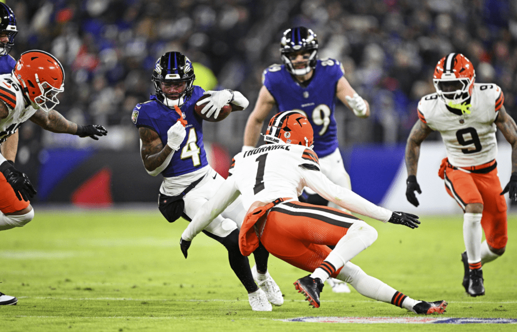 Jan 4, 2025; Baltimore, Maryland, USA; Baltimore Ravens wide receiver Zay Flowers (4) runs the ball during the second quarter as Cleveland Browns safety Juan Thornhill (1) defends at M&T Bank Stadium. Mandatory Credit: Tommy Gilligan-Imagn Images