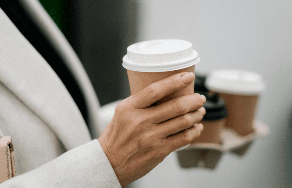 A hand holding a $6 latte in a to-go cup