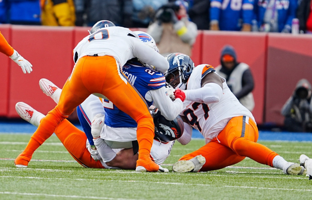 Buffalo Bills running back Ty Johnson (26) gets tackled by Denver Broncos linebacker Jonathon Cooper (0) and Denver Broncos defensive tackle Malcolm Roach (97) during the second half of the Buffalo Bills wild card game against the Denver Broncos at Highmark Stadium in Orchard Park on Jan. 12, 2025.
