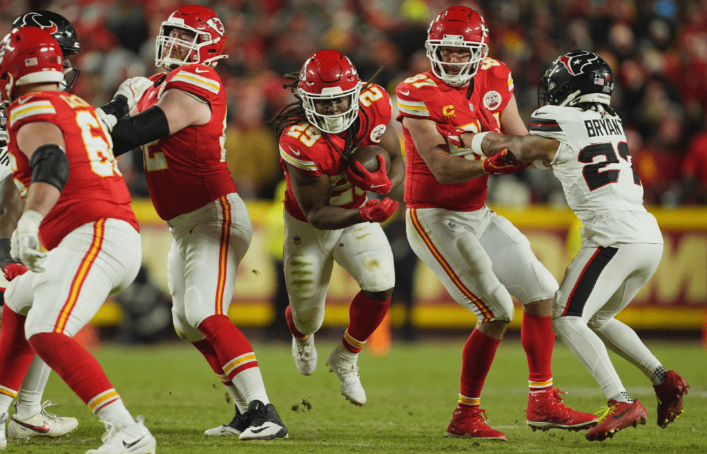 Jan 18, 2025; Kansas City, Missouri, USA; Kansas City Chiefs running back Kareem Hunt (29) runs the ball as tight end Travis Kelce (87) blocks Houston Texans safety Calen Bullock (21) during the fourth quarter of a 2025 AFC divisional round game at GEHA Field at Arrowhead Stadium. Mandatory Credit: Jay Biggerstaff-Imagn Images