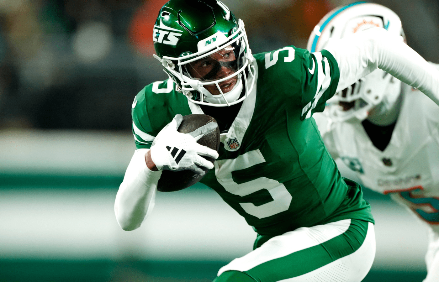 New York Jets wide receiver Garrett Wilson (5) runs with the ball past Miami Dolphins cornerback Jalen Ramsey (5), Sunday January 5, 2025, in East Rutherford