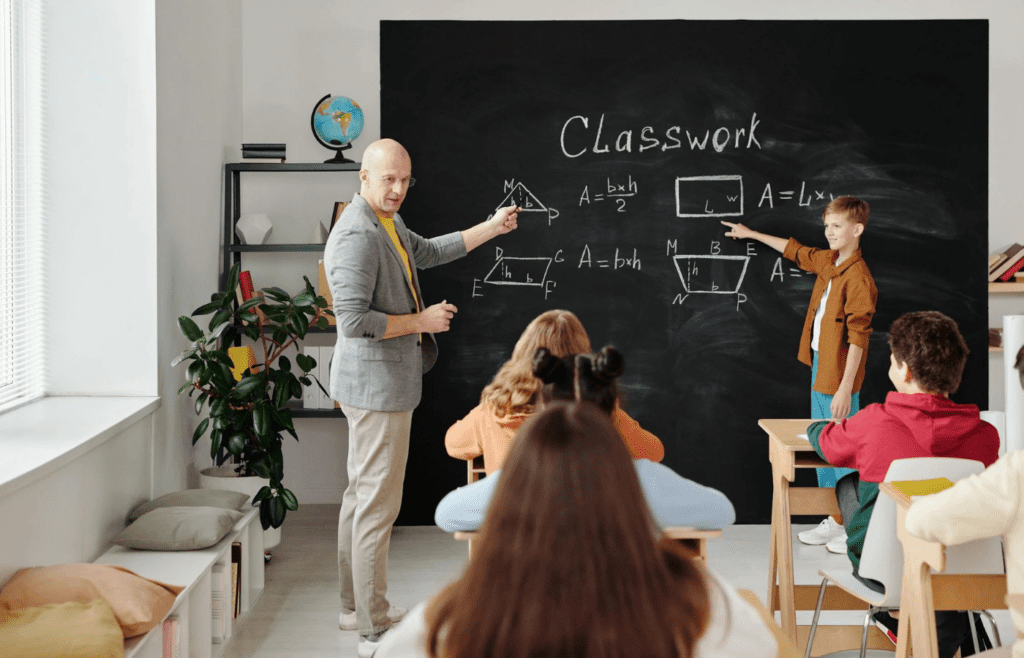 A teacher writing on a chalkboard in a classroom