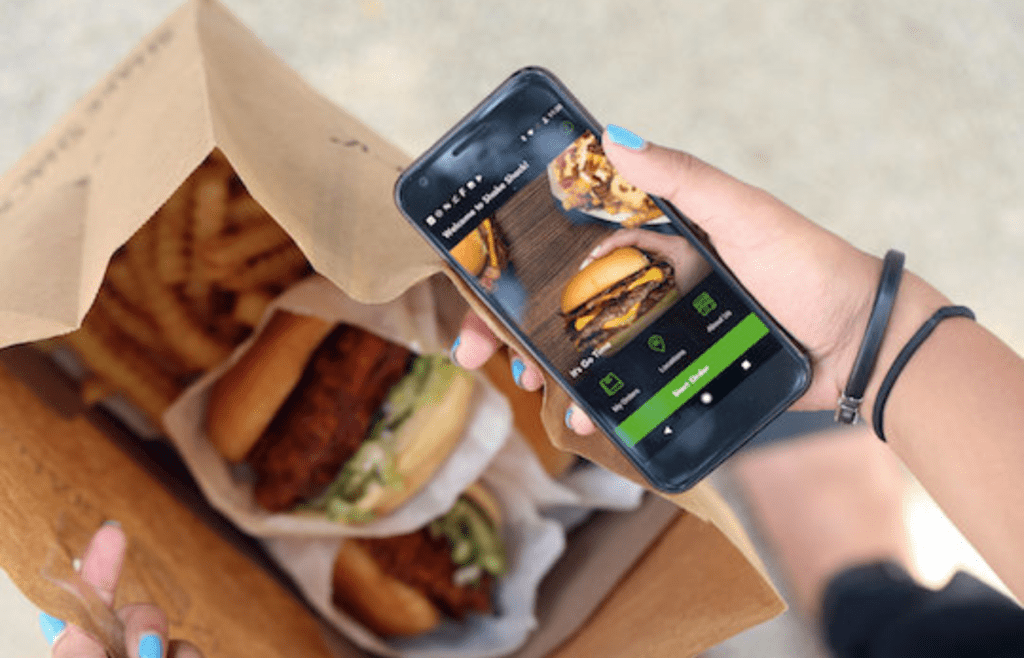 A burger and fries next to a phone app