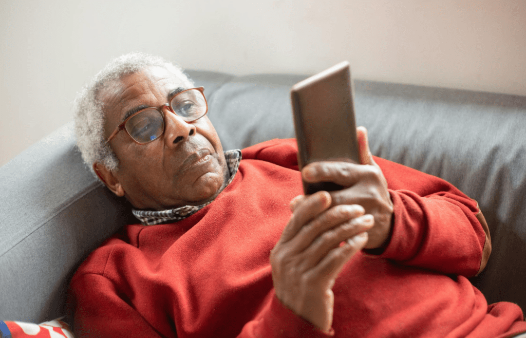 An older adult struggling to use a smartphone.