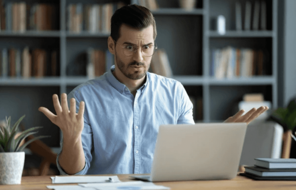 A person shrugging while looking at a computer screen