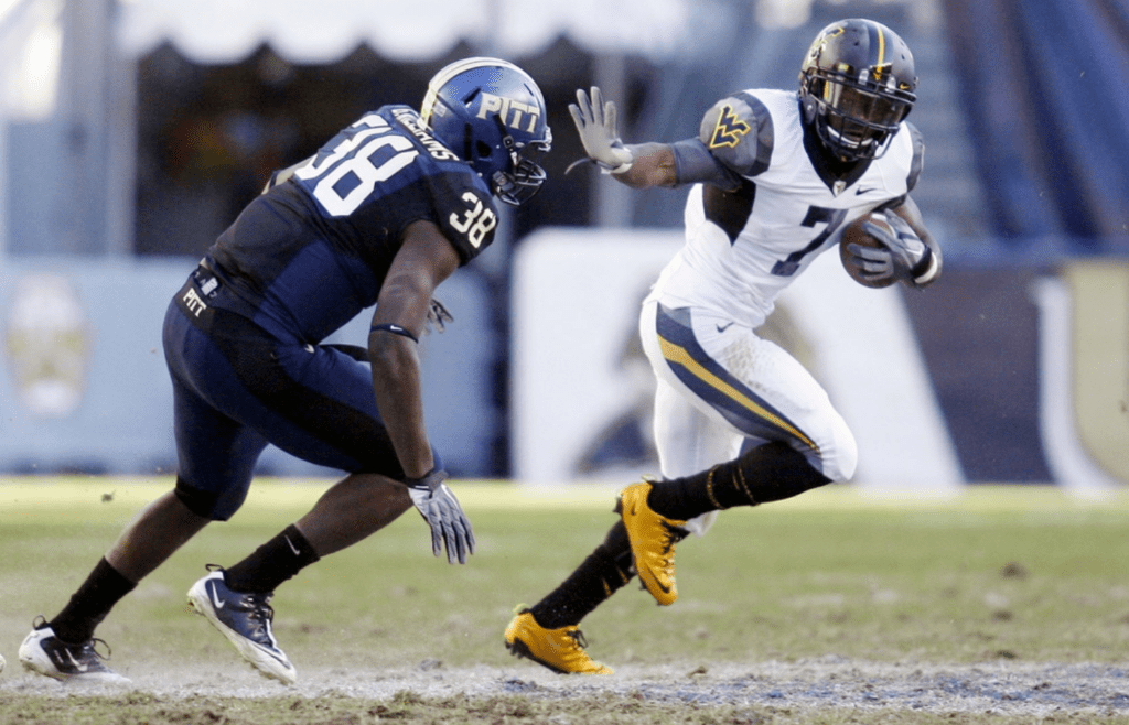 Nov 26, 2010; Pittsburgh, PA, USA; West Virginia Mountaineers running back Noel Devine (7) stiff arms Pittsburgh Panthers linebacker Greg Williams (38) during the fourth quarter at Heinz Field. West Virginia won 35-10. Mandatory Credit: Charles LeClaire-USPRESSWIRE