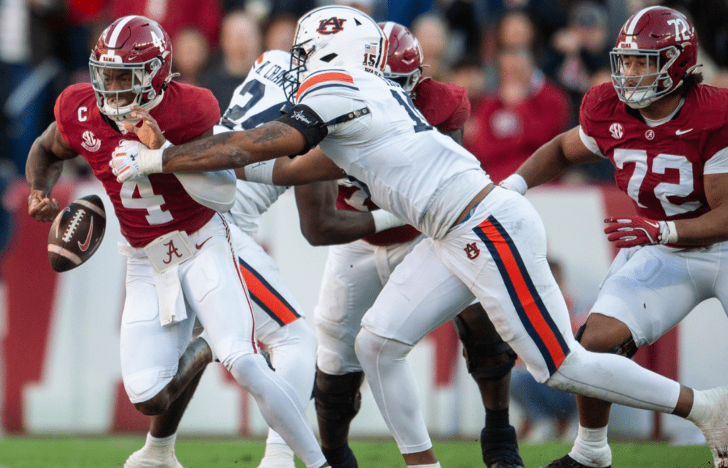 Alabama Crimson Tide quarterback Jalen Milroe (4) fumbles the ball while pressured by Auburn Tigers defensive lineman Keldric Faulk (15) as Auburn Tigers take on Alabama Crimson Tide at Bryant-Denny Stadium in Tuscaloosa, Ala., on Saturday, Nov. 30, 2024. Alabama Crimson Tide leads Auburn Tigers 14-6 at halftime