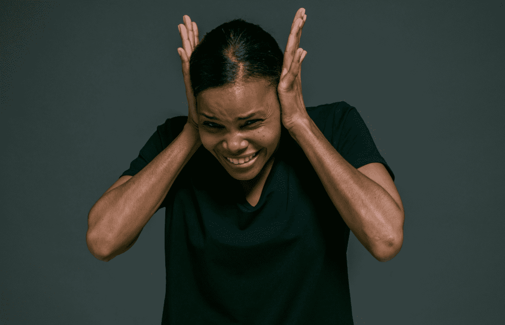A person covering ears in a noisy environment