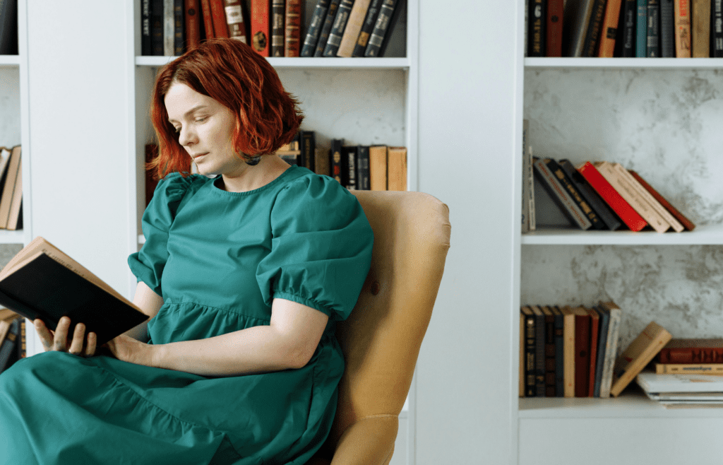 A person surrounded by books, deeply engrossed in reading