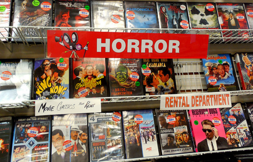 A VHS rental store aisle with faded movie posters